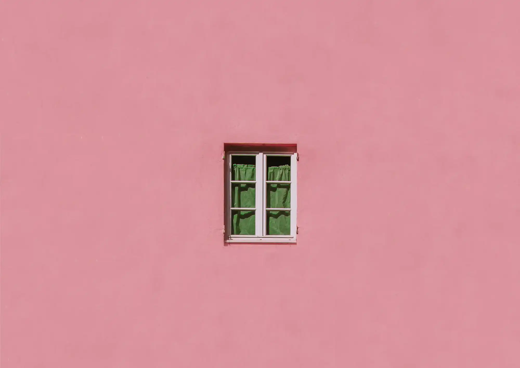 Dämpad rosa fasad med ett fönster i mitten
