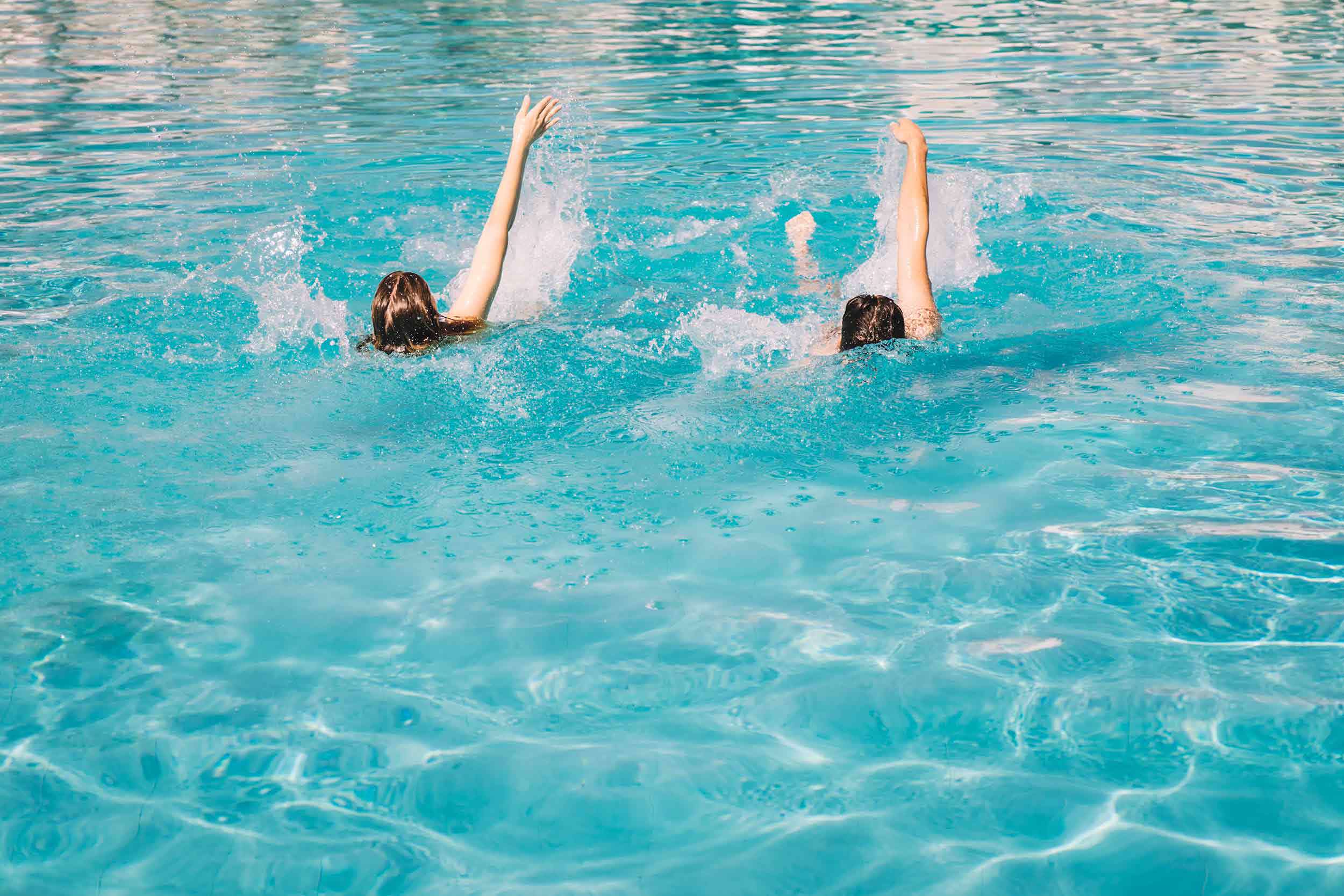 Par som simmar ryggsim i en pool