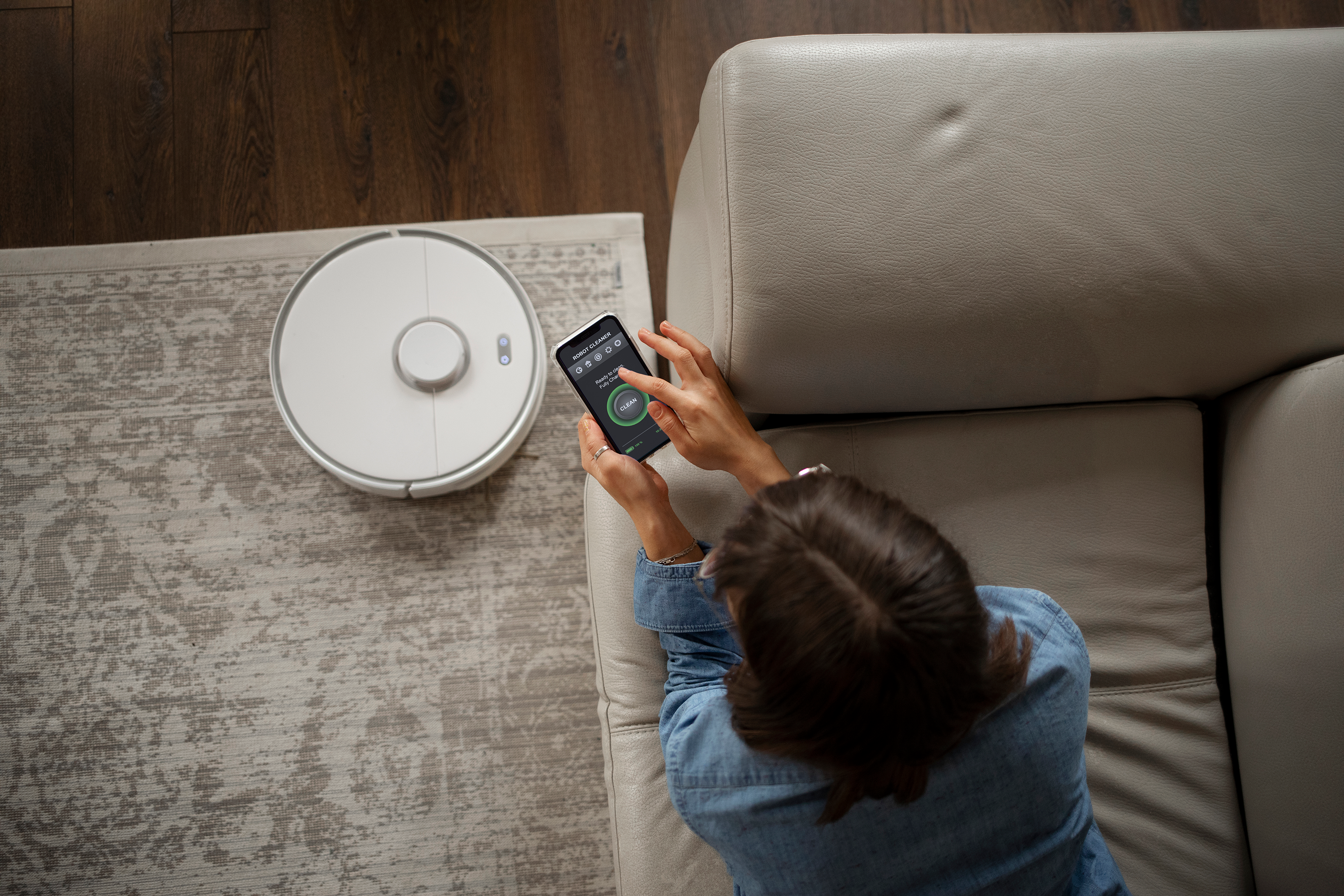 Kvinna som styr robotdammsugare med mobilen