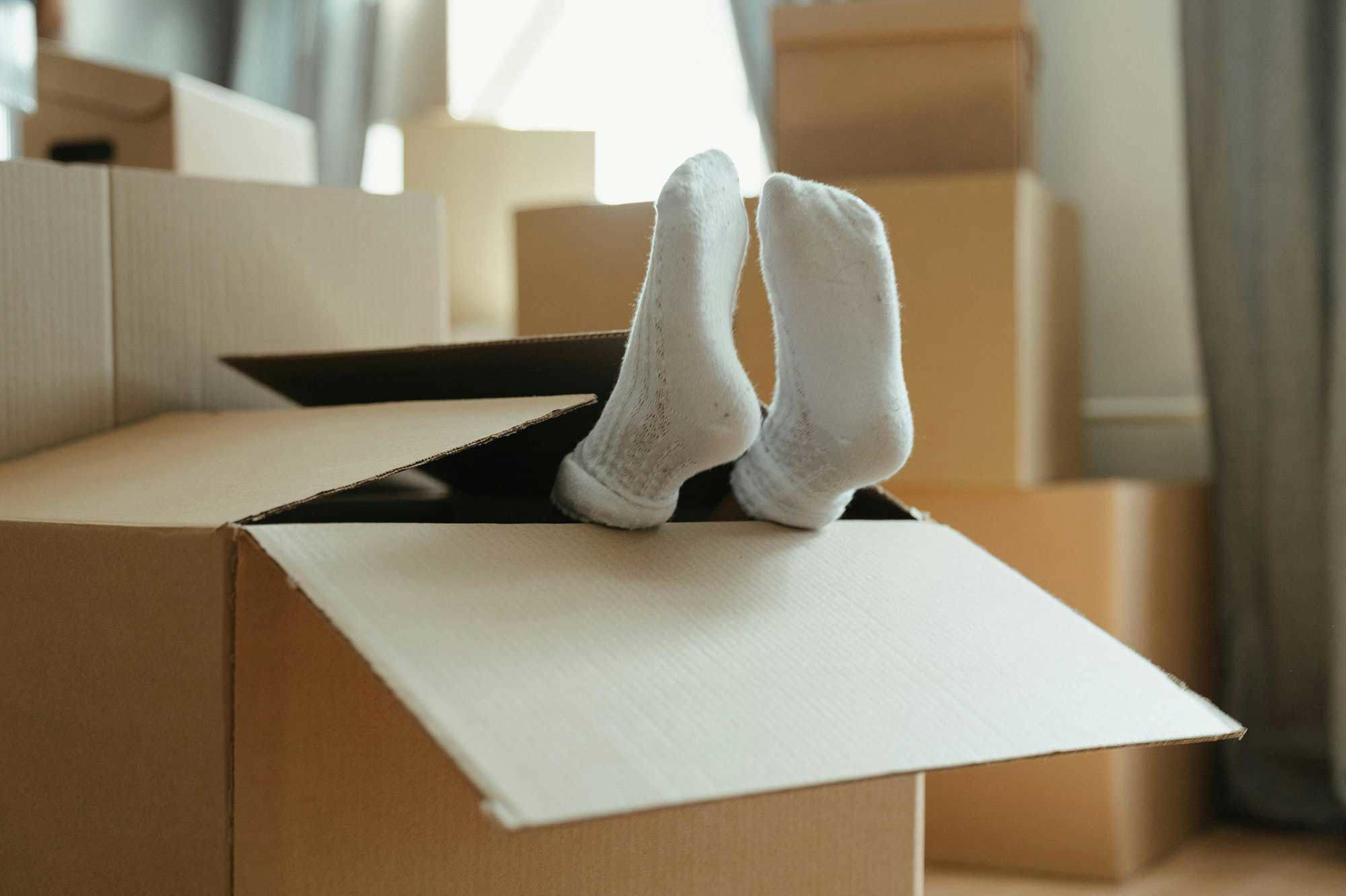 Barn som leker i en flyttlåda där bara fötterna syns